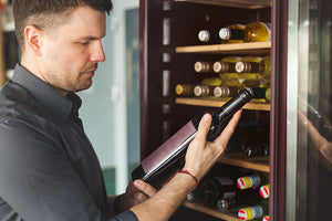 man looking at wine label - buying Swiss wine